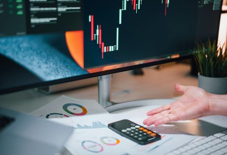 a-person-pointing-at-a-calculator-on-a-desk
