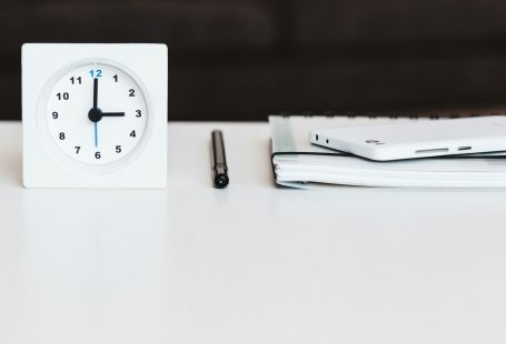 white desk clock near pen and book
