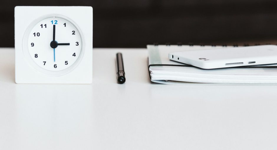 white desk clock near pen and book