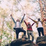 Four friends celebrating on rocky terrain outdoors